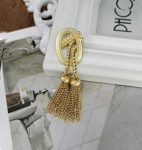 Detail of vintage matte gold tassel brooch with twisted oval frames and metal chain fringe