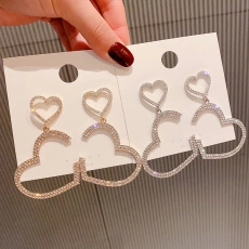 Detail of heart-shaped drop earrings with pavé crystals in gold and silver finish