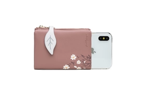 Pink leather wallet with daisy print shown next to a smartphone for size comparison