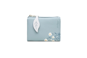 Detail of light blue faux leather wallet featuring a white leaf zipper pull and daisy print