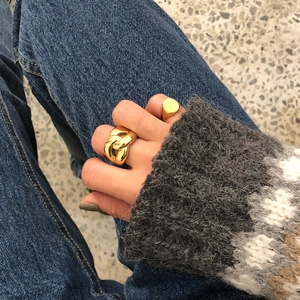 Detail of chunky gold chain link ring and minimalist signet ring on a model hand