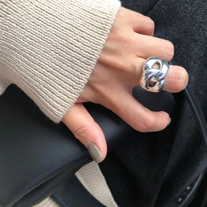 Close-up of a chunky silver irregular chain ring worn with a stylish knit sweater