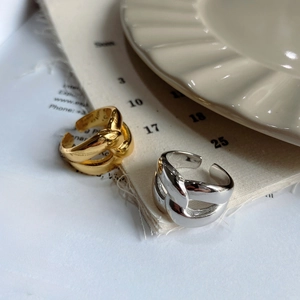 Minimalist thick layered crossover rings in gold and silver finish on artistic props
