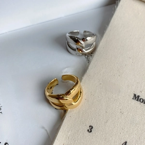 Detail of overlapping gold and silver wide open rings on a lifestyle magazine background