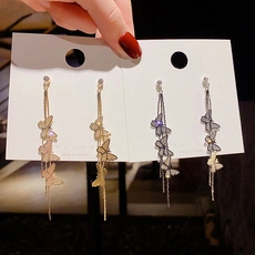 Detail of long butterfly tassel earrings with delicate metal chains in gold and silver