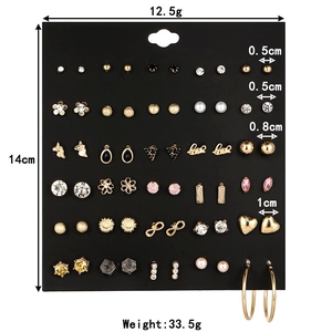 Detailed view of alloy earring set with crystal and pearl studs on black card