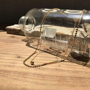 Detailed view of 925 silver golden bead chain necklace on a warm wooden background