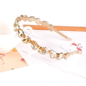 Dettaglio di un cerchietto dorato con strass color ambra su sfondo bianco con decorazioni
