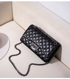 Dettaglio della borsa trapuntata nera con catena in metallo grigio scuro su base beige