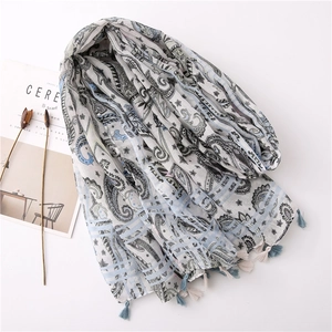 Detail of light gray linen scarf featuring bohemian paisley prints and tasseled edges