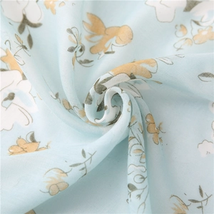 Detailed close-up of light blue floral cotton scarf fabric with soft draped texture