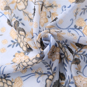Close-up of light blue cotton linen scarf with delicate yellow floral patterns and woven texture