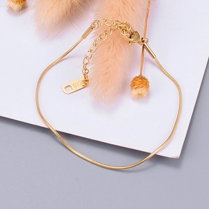 Detail of rose gold snake bone anklet with K18 engraving on a white card background