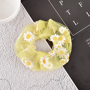 Detail of yellow mesh hair scrunchie featuring delicate white daisy floral patterns