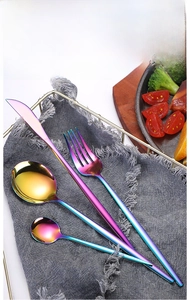 Rainbow gradient stainless steel cutlery set with mirror finish on a rustic table setting