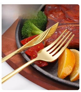 Close-up of golden stainless steel steak knife with sharp saw teeth and mirror finish