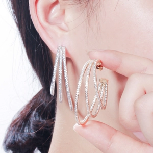 Close-up of triple-layered hoop earrings with shimmering zircons in silver and rose gold