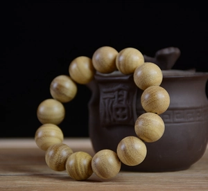 Detailed macro view of 108 wooden beads with natural grain and a Zen ceramic teapot