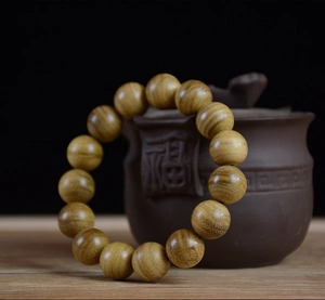 Close-up of golden wood beads with natural texture against a zen tea pot background