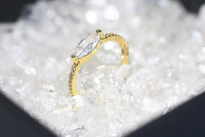Macro shot of marquise-cut zircon engagement ring with pavé diamonds in gold finish