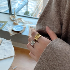 Detailed view of irregular wave pattern rings in gold and silver finish on hand