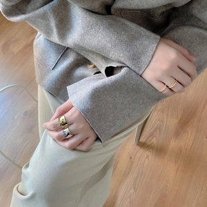 Detailed view of layered gold and silver irregular wave rings worn on hand