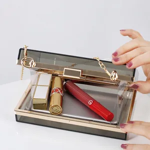 Chic smoke gray acrylic clutch bag with gold frame and chain, showing interior space