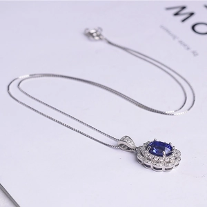 Detailed macro view of a silver sapphire pendant necklace with double-halo diamond accents