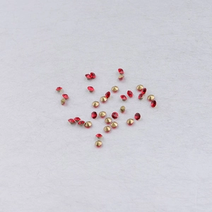 Lot de strass rouges avec bases dorées pour bijoux DIY sur surface blanche