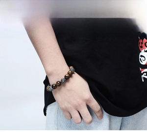 Detailed close-up of tiger eye beads and engraved stainless steel charms on a men's bracelet