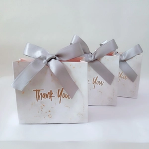Three elegant white marble gift bags with grey ribbon bows and gold Thank You text