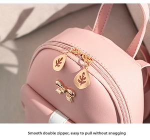 Close-up of dual leaf-shaped zippers and metal bow detail on a pink mini backpack
