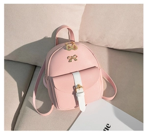 Detail of pink PU leather backpack featuring white flap pocket and golden bow decoration