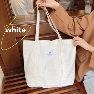Detail of off-white minimalist canvas tote bag with woven label in a vintage cafe setting