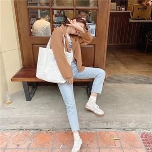 Lifestyle shot of a spacious white canvas tote bag worn on shoulder by a model outdoors