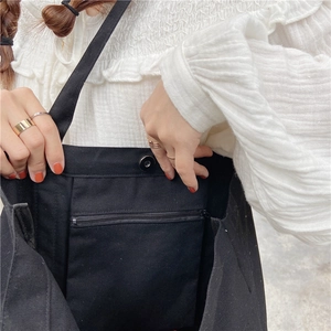 Close-up of black canvas tote bag interior with magnetic snap and zipper pocket