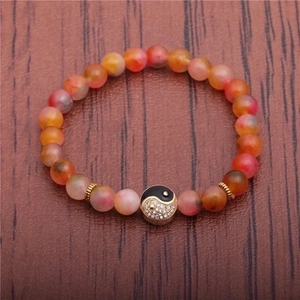 8mm natural agate bead bracelet with yin yang charm on a rustic wood background