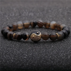 Macro shot of 8mm agate beads bracelet featuring a gold-studded Yin Yang charm centerpiece