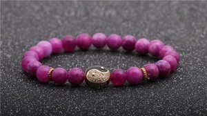 Detailed macro view of 8mm purple agate bead bracelet with golden Tai Chi yin yang charm