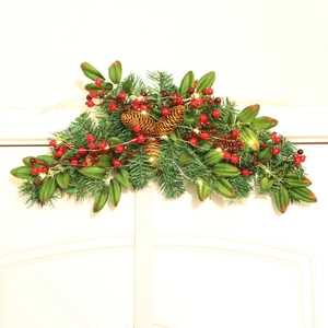 Weihnachtsdekoration mit Tannennadeln roten Beeren Zapfen und warmen LED-Lichtern