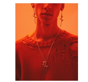 Detail shot of a model wearing a gold rose pin earring and matching rose pendant necklace