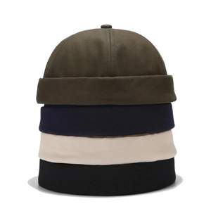 Close-up of four colored cotton docker caps stacked vertically in green navy beige and black