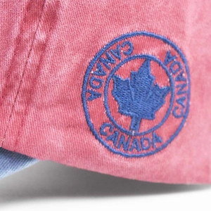 Macro detail of Canada maple leaf embroidery on washed red cotton baseball cap