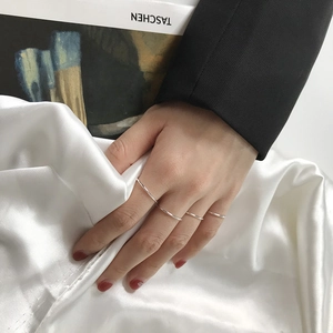 Close-up of four S925 sterling silver minimalist thin rings worn by a model on silk cloth