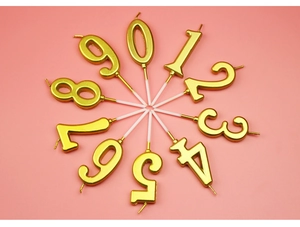 Top view of gold number candles 0-9 arranged in a circle on a pink background