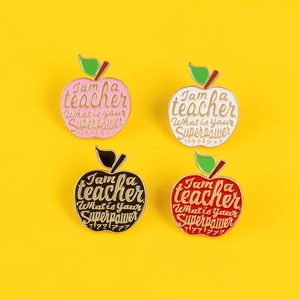 Close-up of four colorful enamel apple brooches for teachers on a bright yellow background