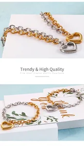 Close-up of gold and silver mixed chain bracelet with a large hollow heart pendant
