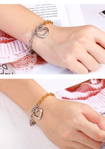 Detailed close-up of two-tone gold and silver heart bracelet with hollow pendant charm