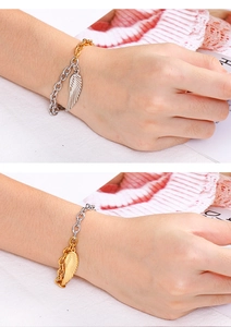 Détail rapproché d'un bracelet en acier inoxydable bicolore avec pendentif aile d'ange