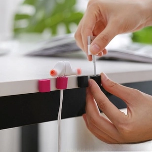Close-up of pink and black silicone cable organizers holding USB wires on desk
